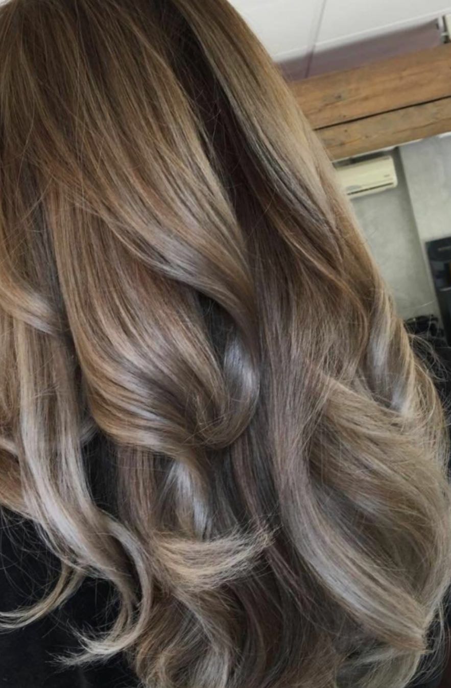 Close-up van lang haar met zachte blonde tinten in golven